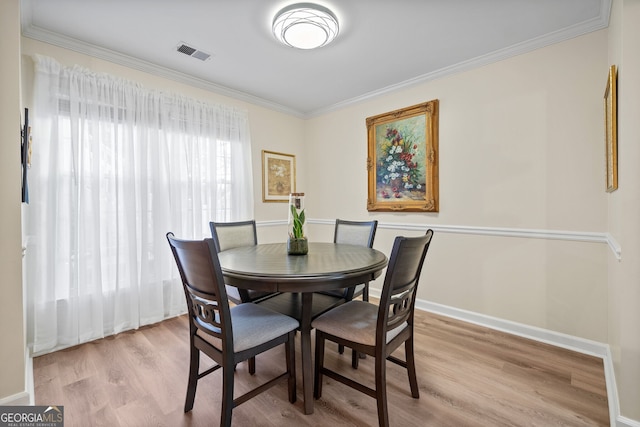 dining area with crown molding and light hardwood / wood-style floors