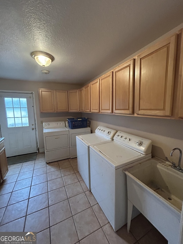 laundry area featuring light tile patterned floors, cabinet space, a sink, and separate washer and dryer