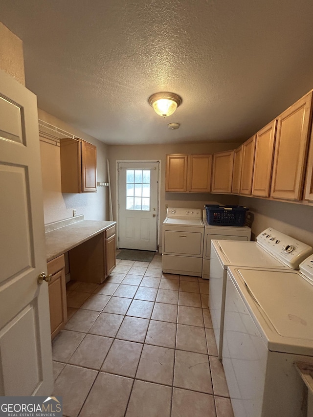 washroom with cabinet space, light tile patterned flooring, a textured ceiling, and independent washer and dryer