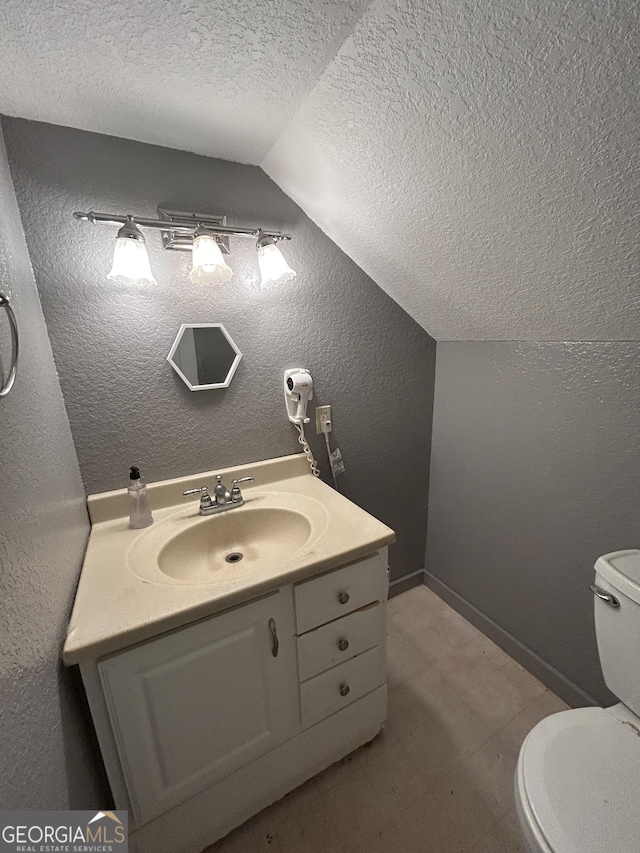 bathroom featuring lofted ceiling, a textured wall, a textured ceiling, and vanity