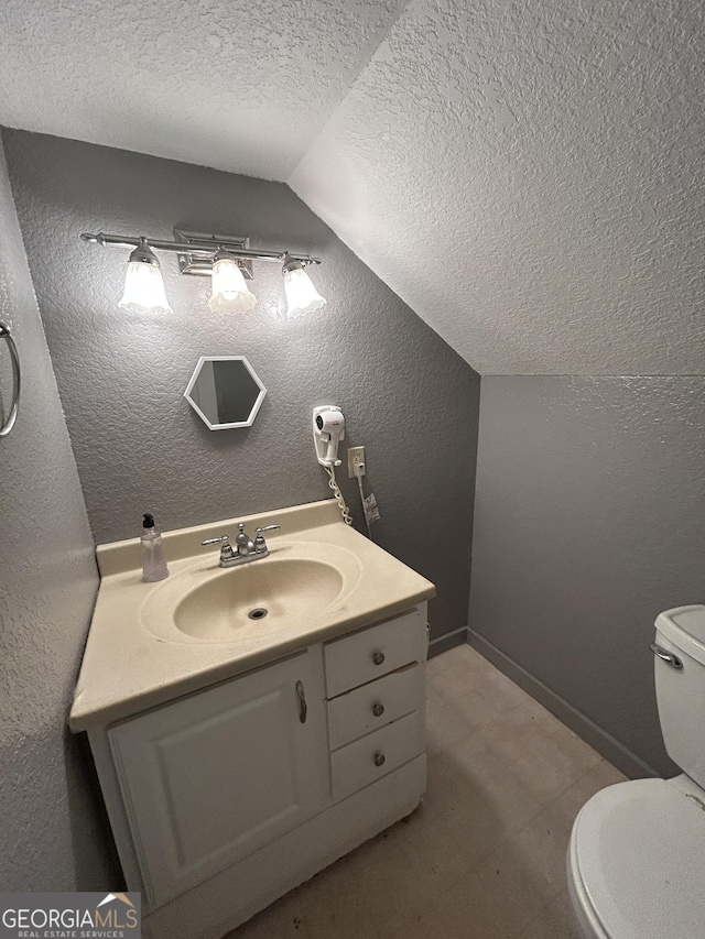 382 Lower Lovelace Rd, West Point, GA 31833 - bathroom featuring lofted ceiling, a textured ceiling, toilet, a textured wall, and vanity