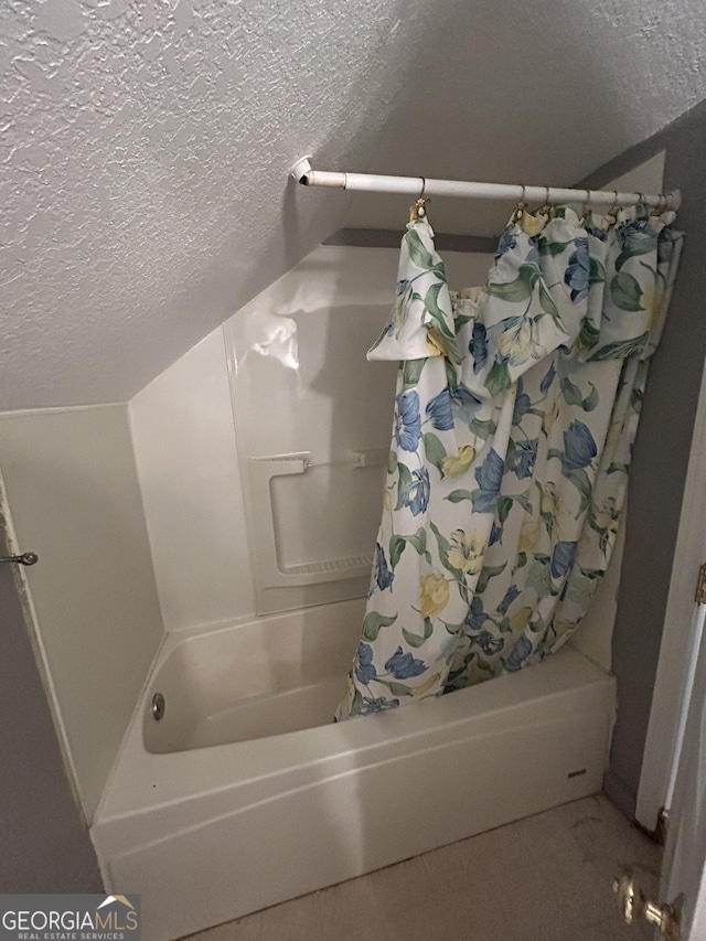 bathroom featuring a textured ceiling, tile patterned flooring, lofted ceiling, and shower / tub combo with curtain