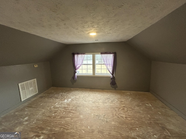 additional living space featuring lofted ceiling, visible vents, and a textured ceiling