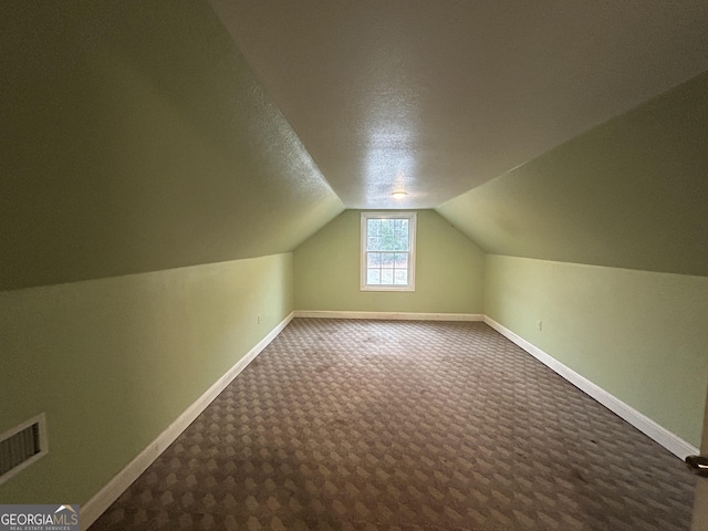 bonus room featuring lofted ceiling, visible vents, carpet flooring, a textured ceiling, and baseboards