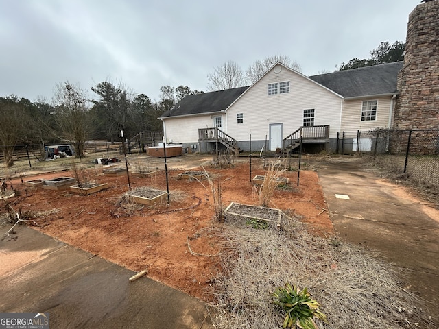 back of house featuring a vegetable garden, a chimney, and fence