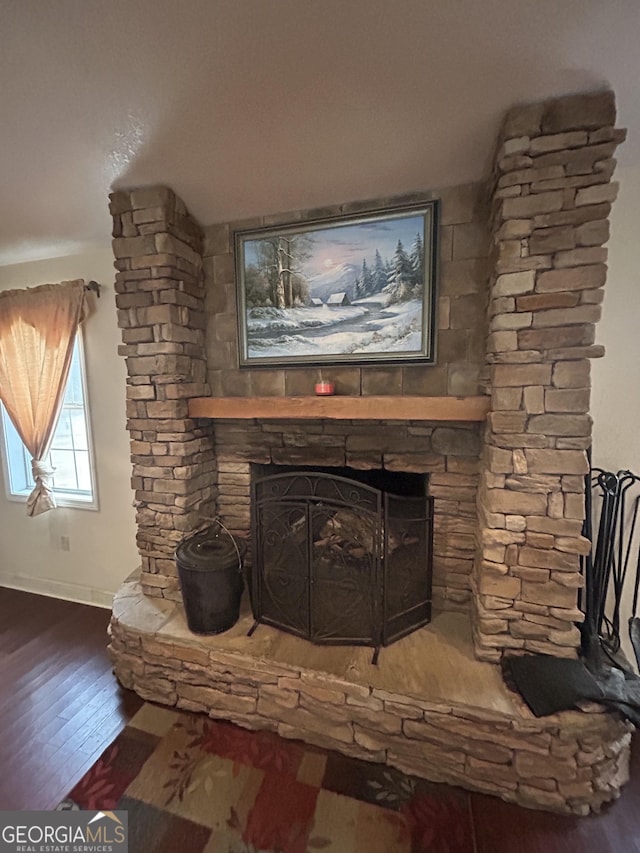 interior details with a stone fireplace, wood finished floors, and baseboards