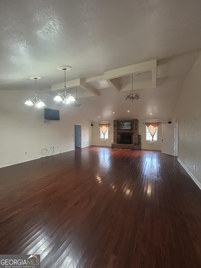 unfurnished living room featuring dark wood finished floors, vaulted ceiling, a textured ceiling, a fireplace, and a chandelier