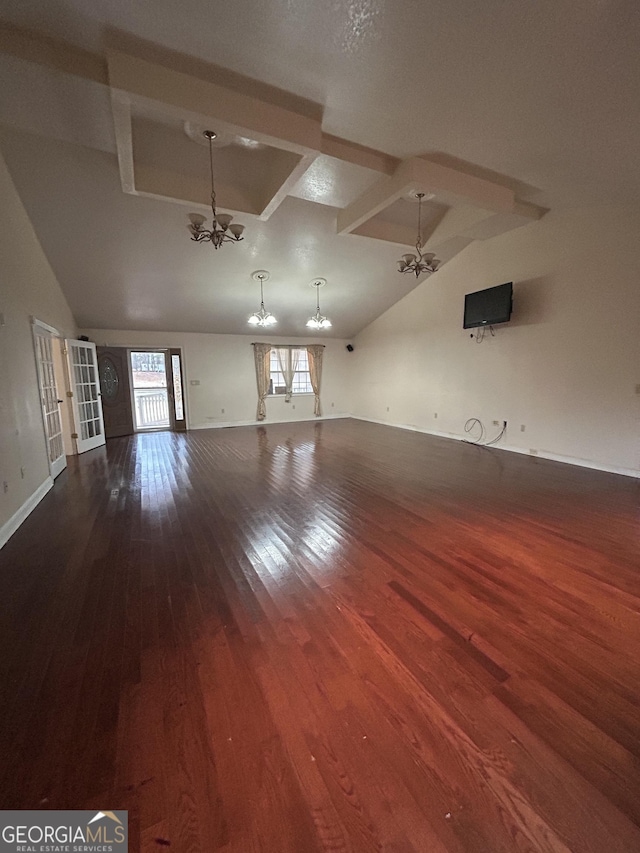 unfurnished living room with dark wood-type flooring, lofted ceiling, a notable chandelier, and baseboards