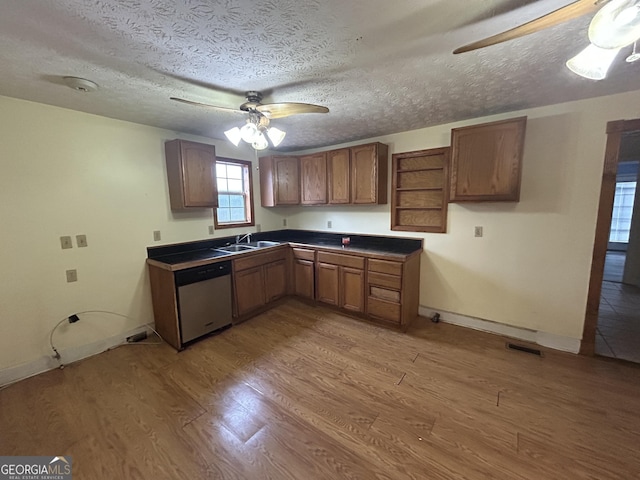 kitchen featuring dark countertops, ceiling fan, light wood-type flooring, stainless steel dishwasher, and a sink