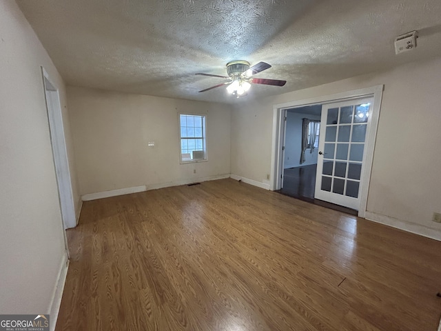 empty room featuring ceiling fan, a textured ceiling, baseboards, and wood finished floors