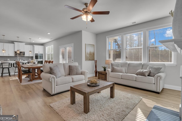 living room featuring a wealth of natural light, ceiling fan, and light wood-type flooring