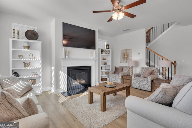 720 Lanarck Way, Peachtree City, GA 30269 - living area featuring light wood finished floors, ceiling fan, stairs, and a glass covered fireplace