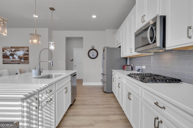 kitchen featuring white cabinetry, sink, hanging light fixtures, and appliances with stainless steel finishes