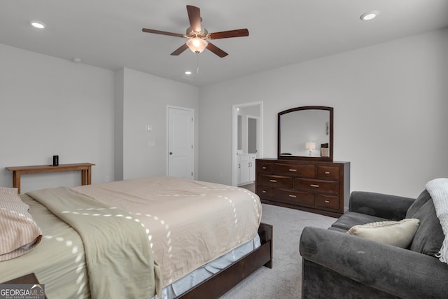 carpeted bedroom with ensuite bathroom and ceiling fan