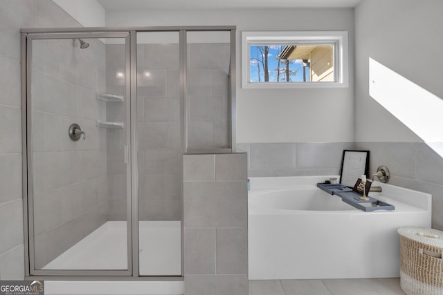 bathroom with tile walls, tile patterned floors, and shower with separate bathtub