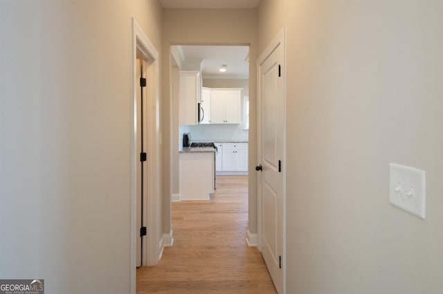 corridor featuring ornamental molding and light hardwood / wood-style floors