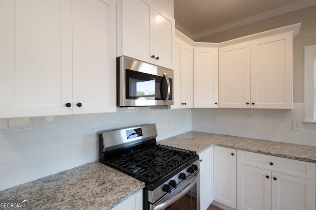 kitchen featuring crown molding, white cabinetry, backsplash, stainless steel appliances, and light stone counters