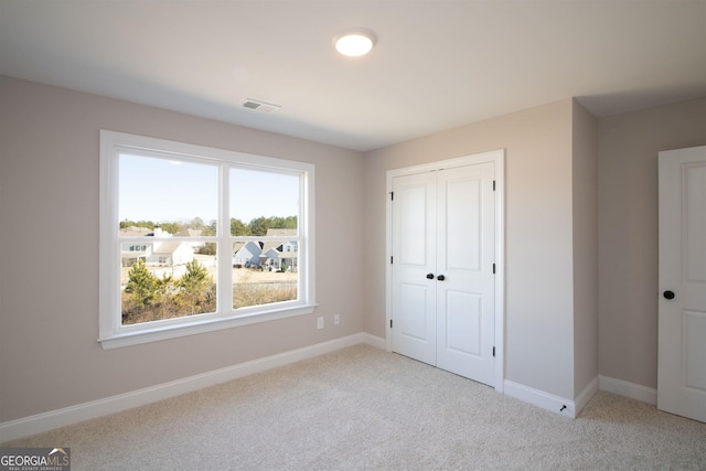 unfurnished bedroom with light colored carpet and a closet