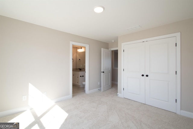 unfurnished bedroom featuring light colored carpet, connected bathroom, and a closet