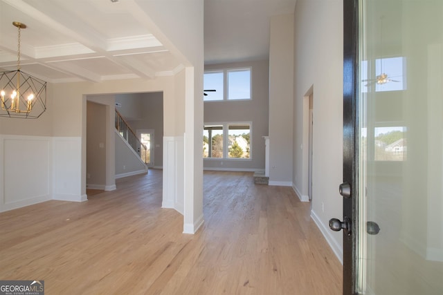 foyer featuring ceiling fan with notable chandelier, beamed ceiling, coffered ceiling, light hardwood / wood-style floors, and crown molding