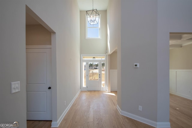 foyer with a high ceiling, coffered ceiling, and light hardwood / wood-style flooring