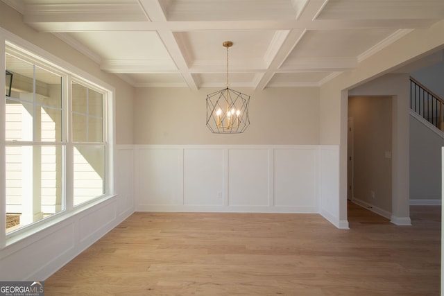 unfurnished dining area with coffered ceiling, beam ceiling, light hardwood / wood-style flooring, and a chandelier