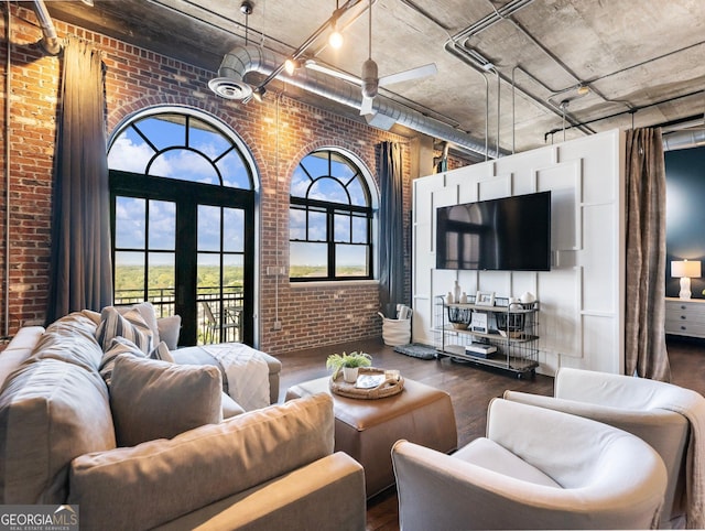 living room with a towering ceiling, brick wall, and dark hardwood / wood-style floors