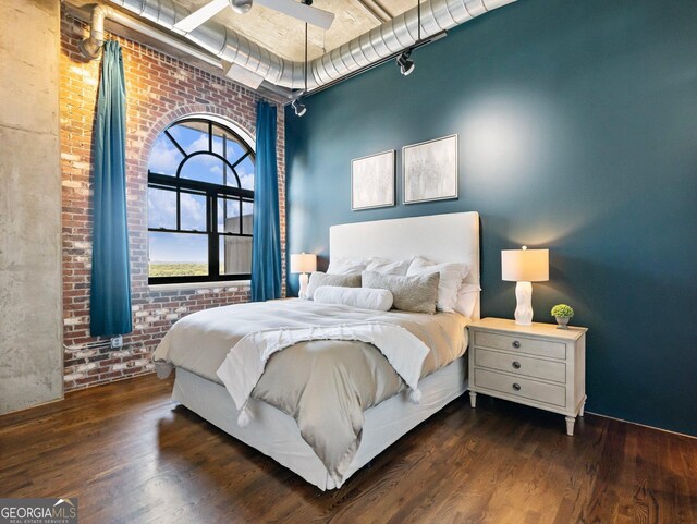 bedroom featuring dark hardwood / wood-style flooring and brick wall