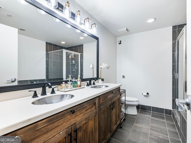 bathroom with a shower with door, vanity, tile patterned flooring, and toilet