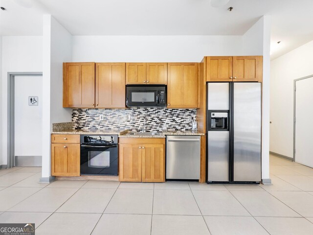 kitchen featuring tasteful backsplash, light tile patterned floors, and black appliances