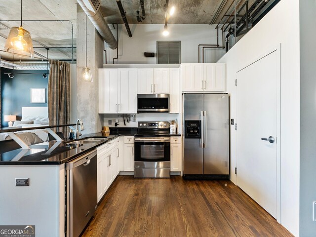 kitchen featuring appliances with stainless steel finishes, decorative light fixtures, white cabinetry, sink, and dark wood-type flooring