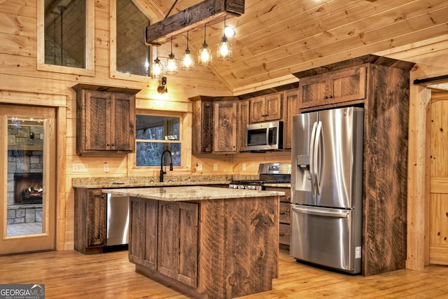 kitchen with appliances with stainless steel finishes, pendant lighting, a center island, wood ceiling, and light stone countertops