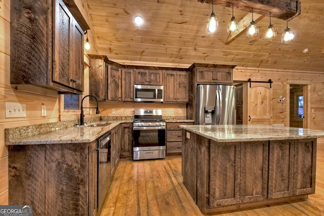 kitchen featuring sink, decorative light fixtures, a kitchen island, stainless steel appliances, and a barn door