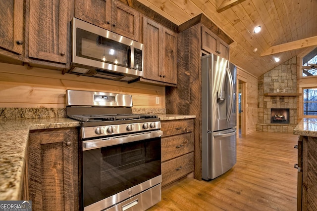 kitchen featuring vaulted ceiling, wooden ceiling, stainless steel appliances, a fireplace, and light hardwood / wood-style floors