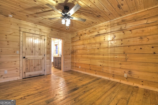 unfurnished room with hardwood / wood-style floors, wooden walls, wooden ceiling, and ceiling fan