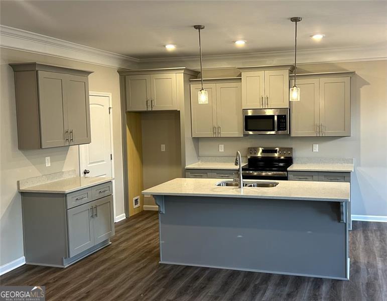 kitchen with pendant lighting, stainless steel appliances, a kitchen island with sink, and gray cabinetry