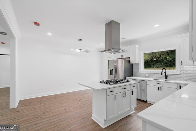 kitchen with island exhaust hood, appliances with stainless steel finishes, a kitchen island, and white cabinets