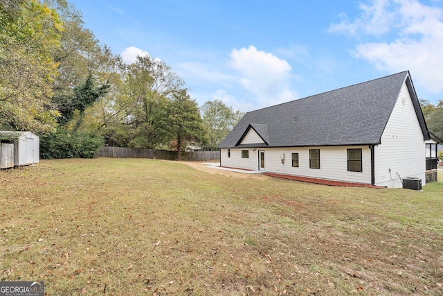 back of house with a storage shed, central AC unit, and a lawn