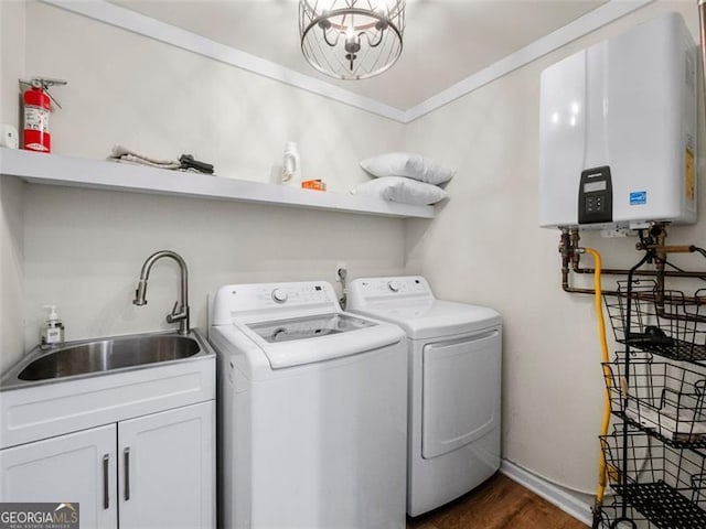 laundry area with washing machine and clothes dryer, tankless water heater, sink, crown molding, and cabinets