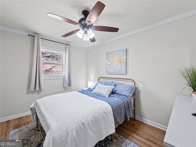 bedroom with wood-type flooring, ceiling fan, and crown molding