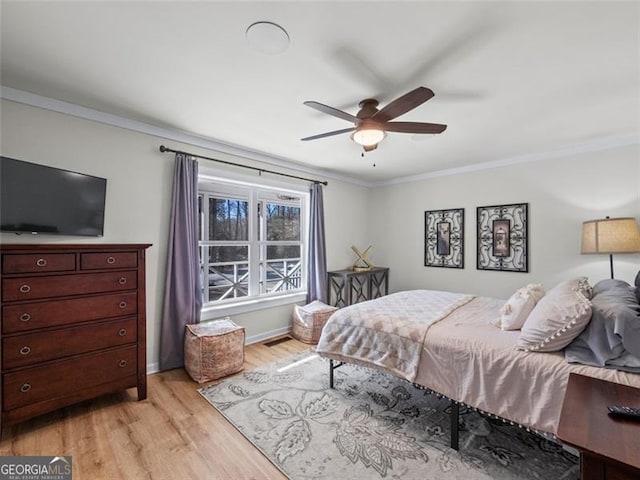 bedroom featuring crown molding, light hardwood / wood-style flooring, and ceiling fan