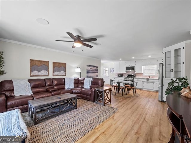 living room with ceiling fan, ornamental molding, and light hardwood / wood-style floors