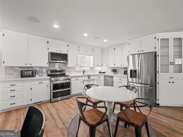 kitchen featuring tasteful backsplash, light hardwood / wood-style flooring, white cabinets, and appliances with stainless steel finishes