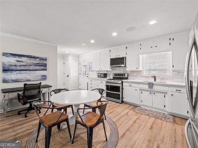 kitchen featuring white cabinetry, appliances with stainless steel finishes, sink, and light hardwood / wood-style flooring