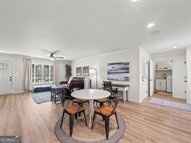 dining room with sink, separate washer and dryer, ornamental molding, ceiling fan, and light hardwood / wood-style floors