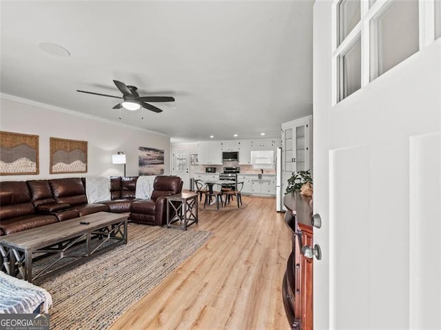 living room with ornamental molding, ceiling fan, and light hardwood / wood-style flooring