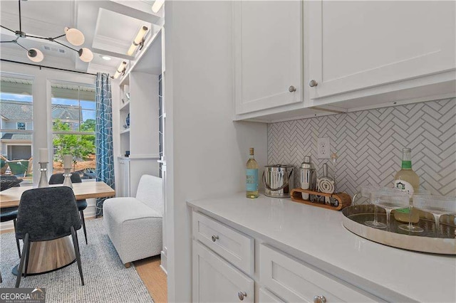 bar featuring white cabinetry, light hardwood / wood-style floors, and tasteful backsplash