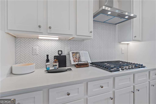 kitchen featuring white cabinetry, wall chimney exhaust hood, stainless steel gas cooktop, and backsplash