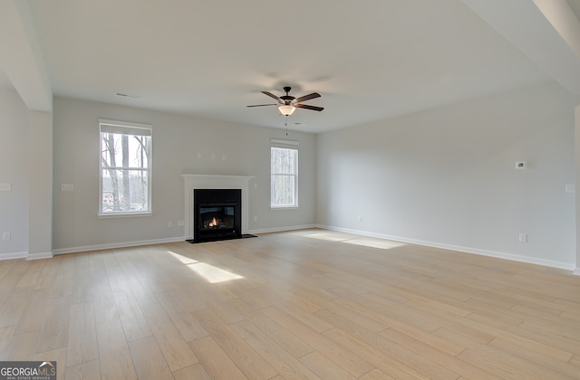 unfurnished living room featuring visible vents, a fireplace with flush hearth, baseboards, and light wood finished floors