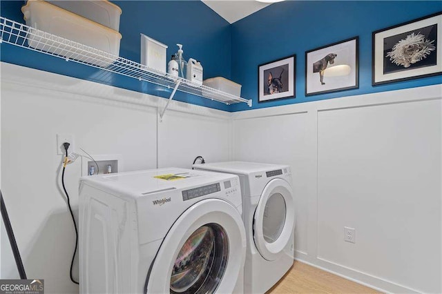 clothes washing area featuring separate washer and dryer and light hardwood / wood-style floors